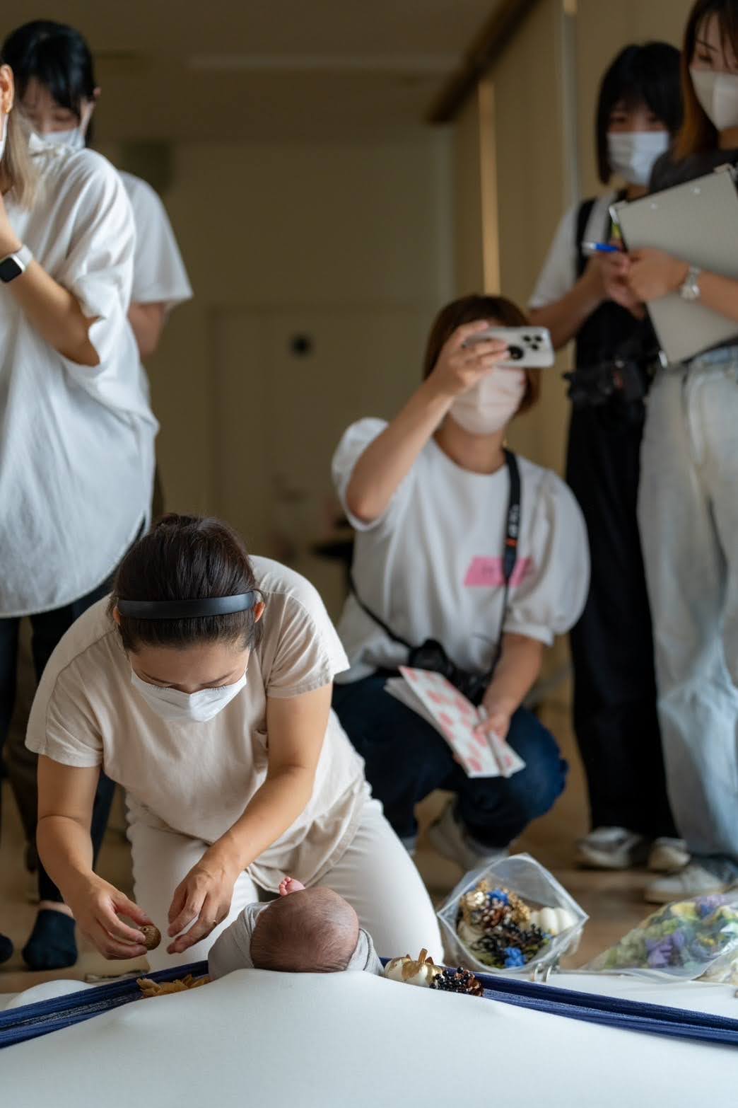 対面授業で水沢あゆみが赤ちゃんにポージングを行い、受講生が撮影している様子
